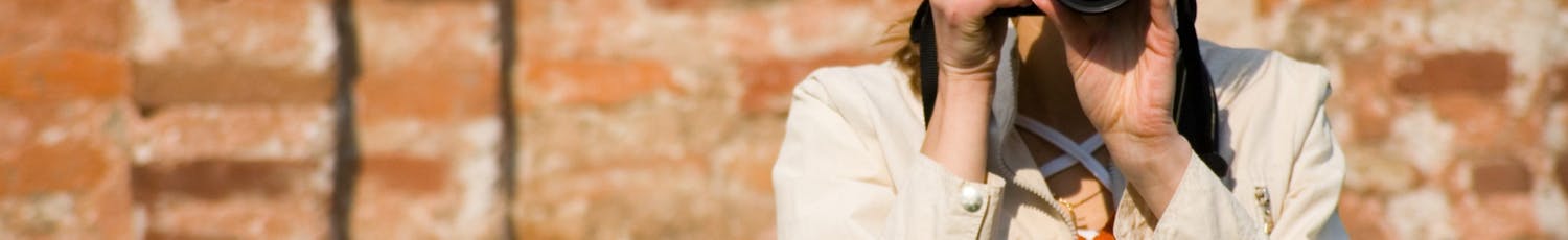 Kvinde fotograferer med ekstern flash på kameraet på solskinsdag